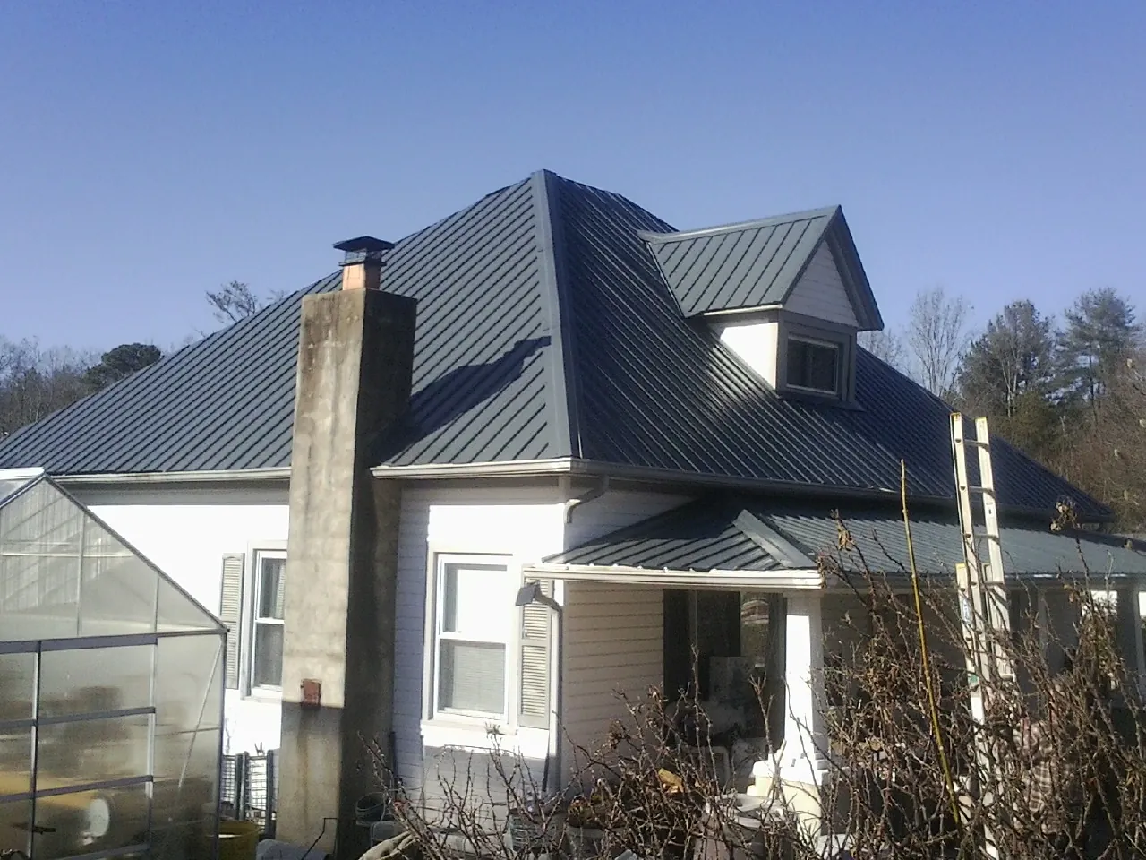 Dark blue standing seam metal roof on a white farmhouse with dormer — Slate & Tile Roof Repair by Roofing Brothers in Dowagiac
