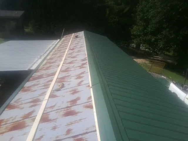 Old rusted panels beside newly installed green metal roofing — Wind Damage Roof Repair by Roofing Brothers in Dowagiac
