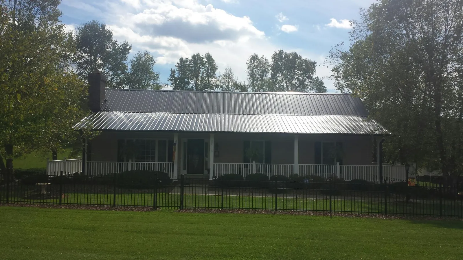 Gray metal roof on a brick ranch with a full width front porch — Gutter Guard Installation work by our crew in Dowagiac