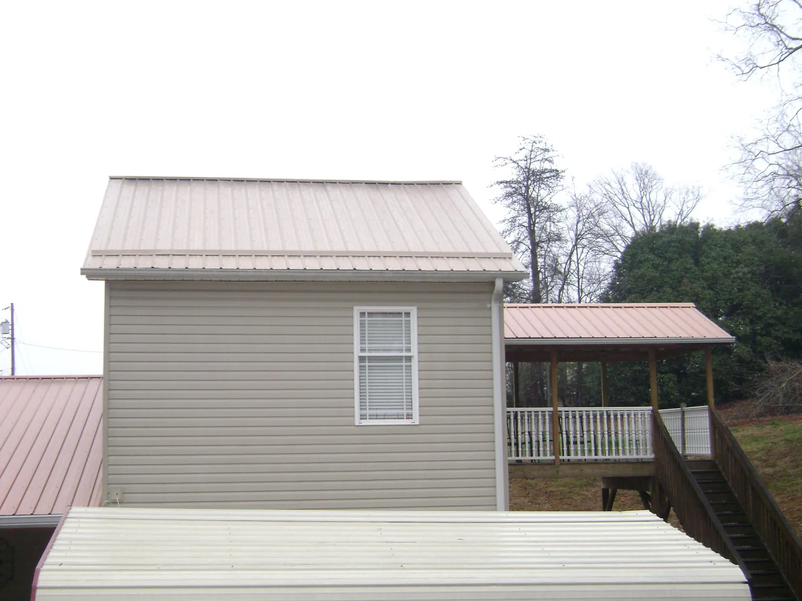Tan metal roofs on a two story addition and attached porch, from a Roof Replacement job in Dowagiac