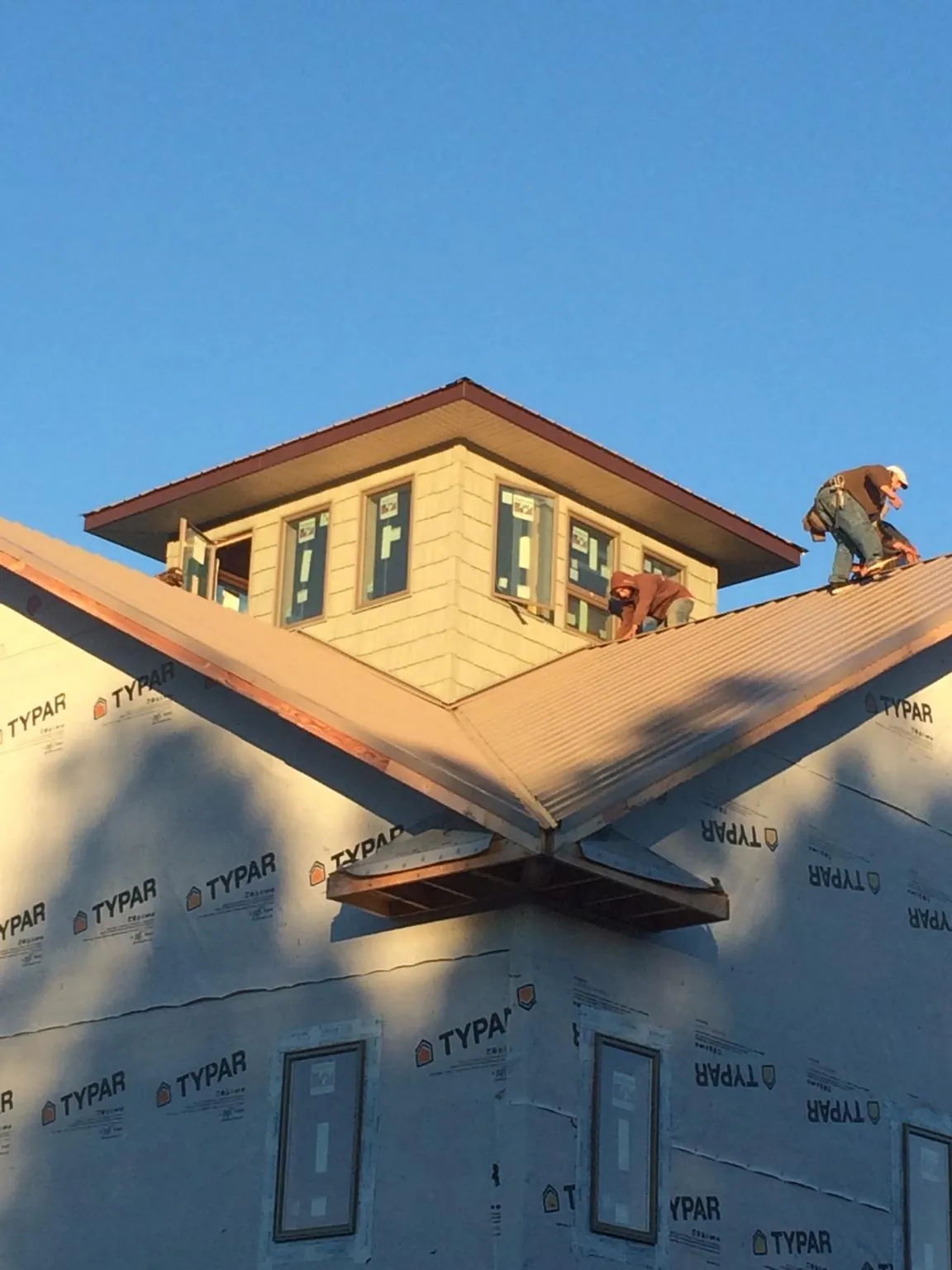 Roofers working around a rooftop cupola on a new metal roof at sunset — Roof Waterproofing in Dowagiac by Roofing Brothers